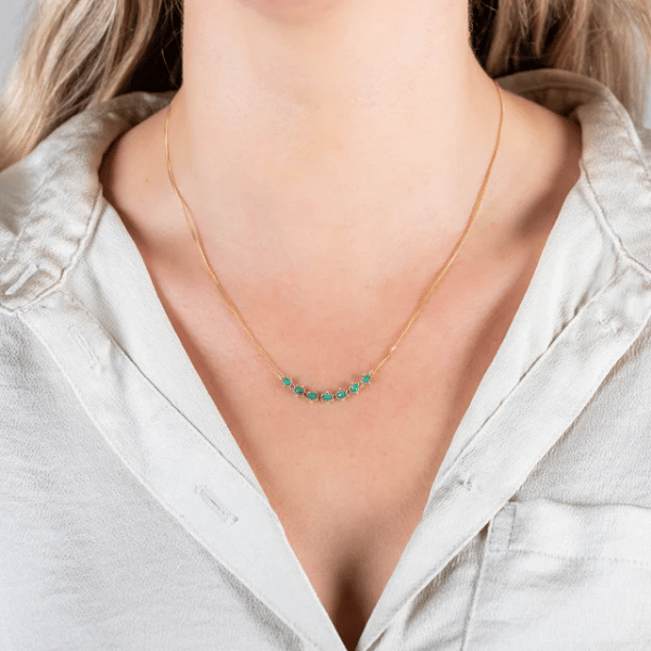 18k yellow gold chain necklace featuring a delicate row of handwoven emerald gemstones worn around the neck.