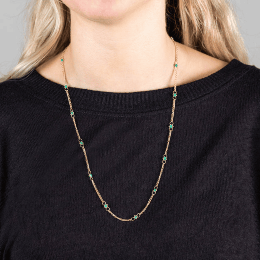 18k yellow gold chain necklace featuring hand-woven emerald stones worn around the neck.