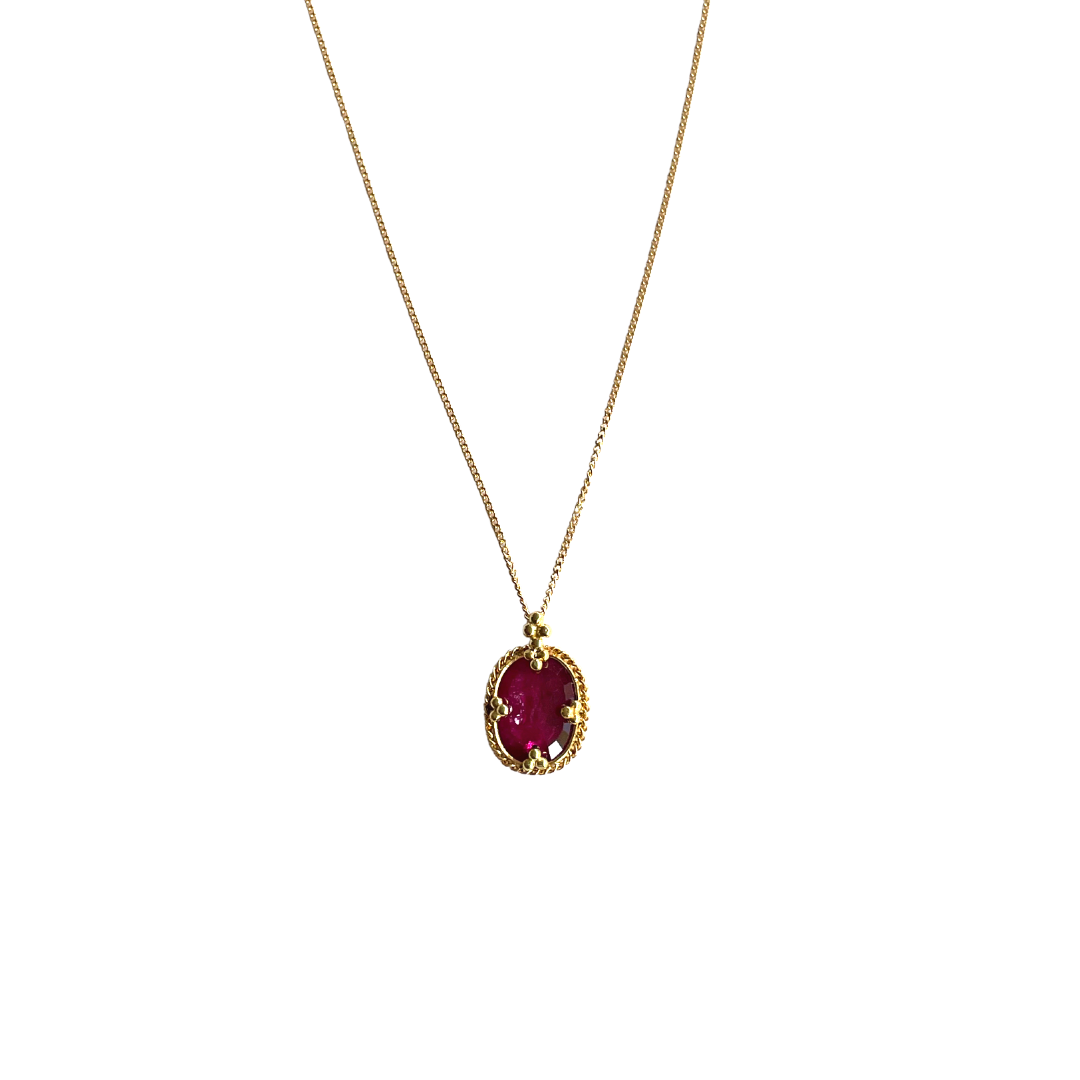 Oval faceted ruby pendant in an 18k yellow gold rope setting on a delicate gold chain.