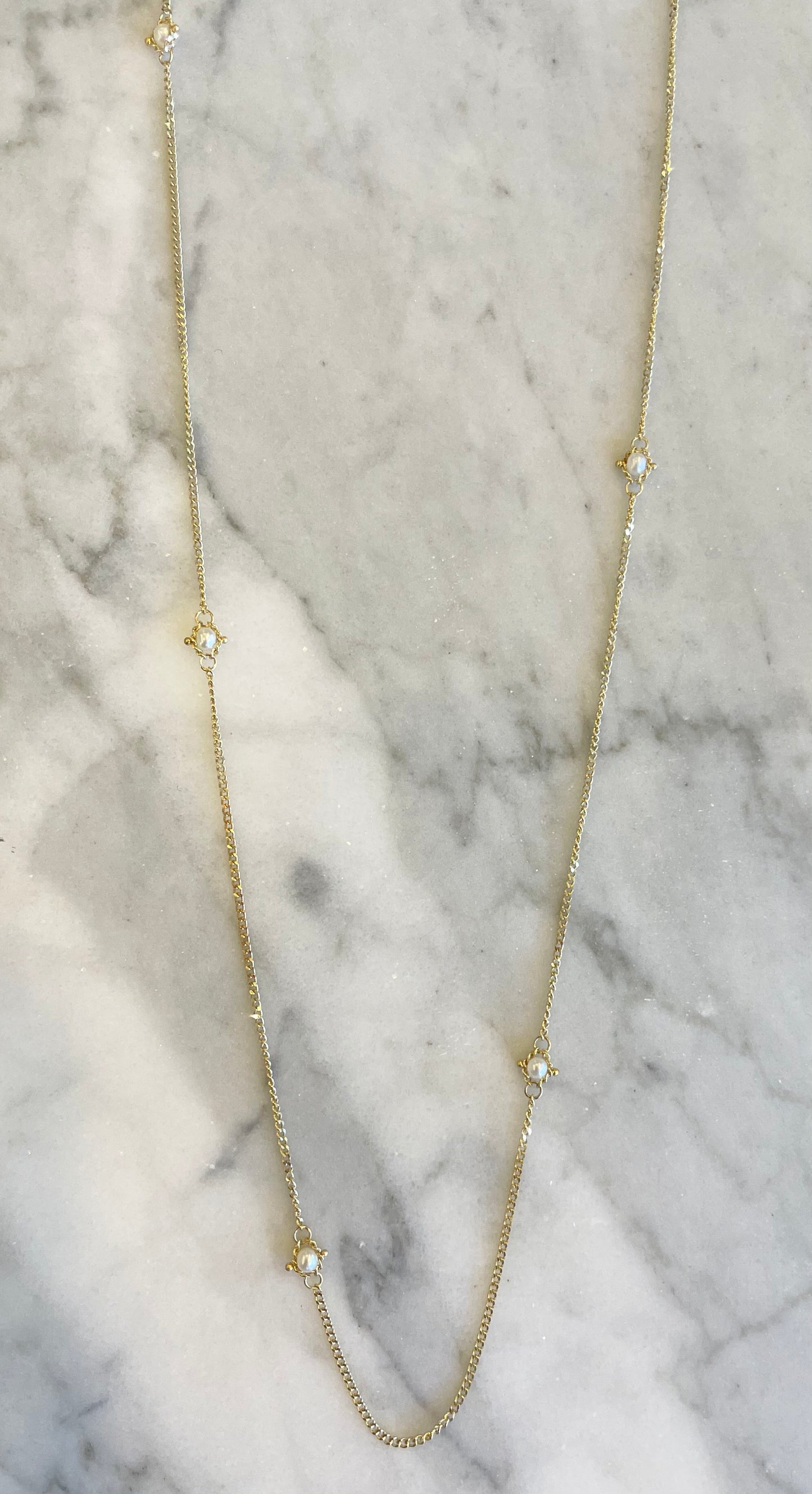 18k yellow gold station necklace featuring delicate freshwater pearl accents on a shimmering, hand-woven chain.