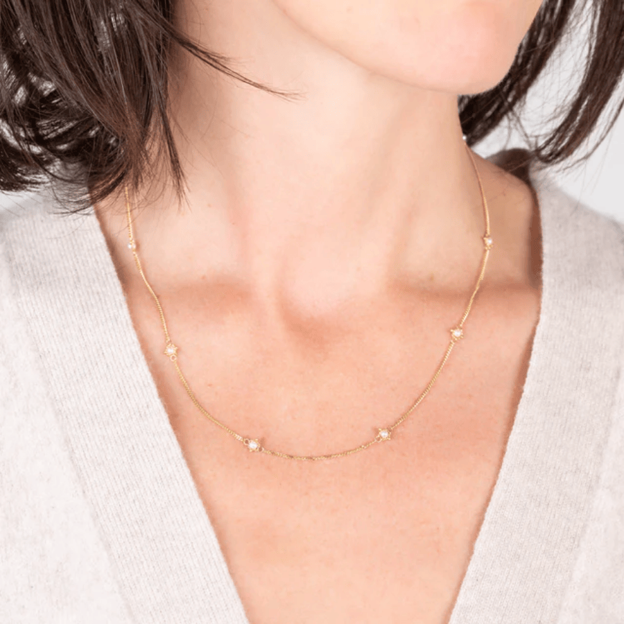 Delicate 18k yellow gold station necklace featuring small freshwater pearls on a fine, hand-woven shimmering chain.