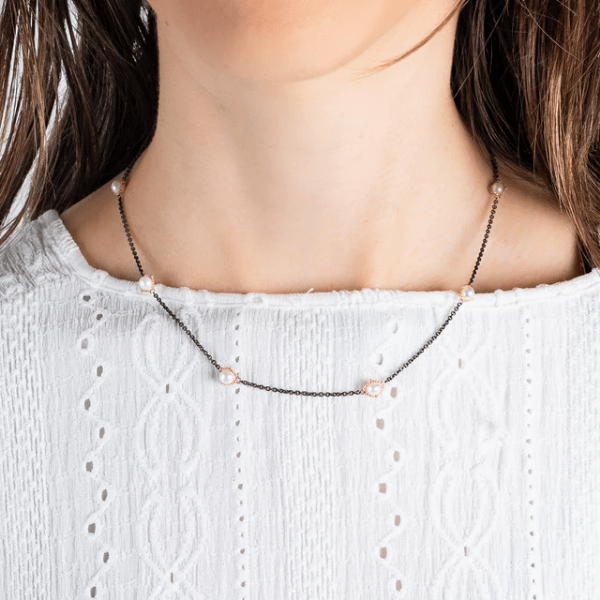 Freshwater pearl station necklace with 18k gold settings on an oxidized sterling silver chain worn on a neck.