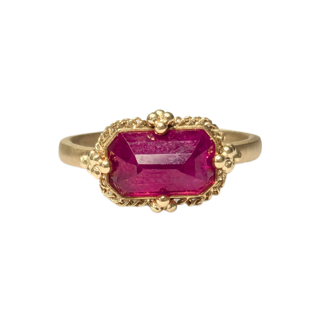 3.18 carat east-west ruby ring in 18k yellow gold with a decorative filigree setting.