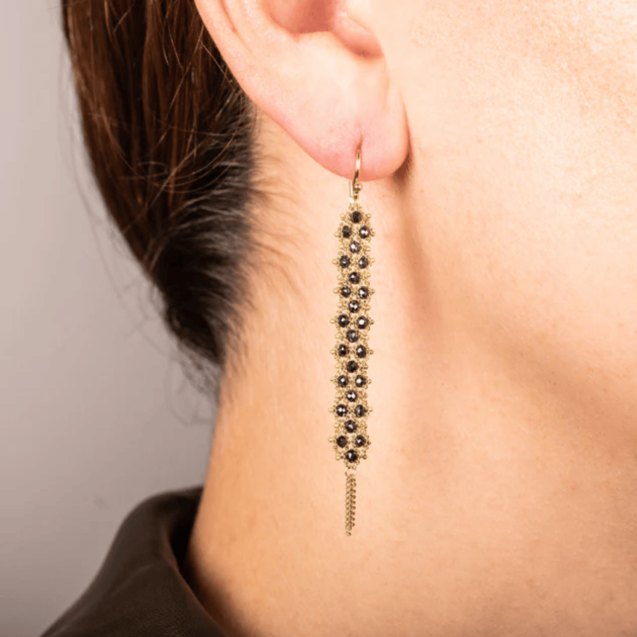 Long drop earrings featuring woven black diamonds set in 18K yellow gold with delicate golden chain accents.