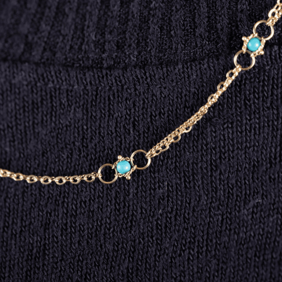 18k yellow gold chain necklace featuring delicate turquoise stones set between small gold hoops on a dark background.