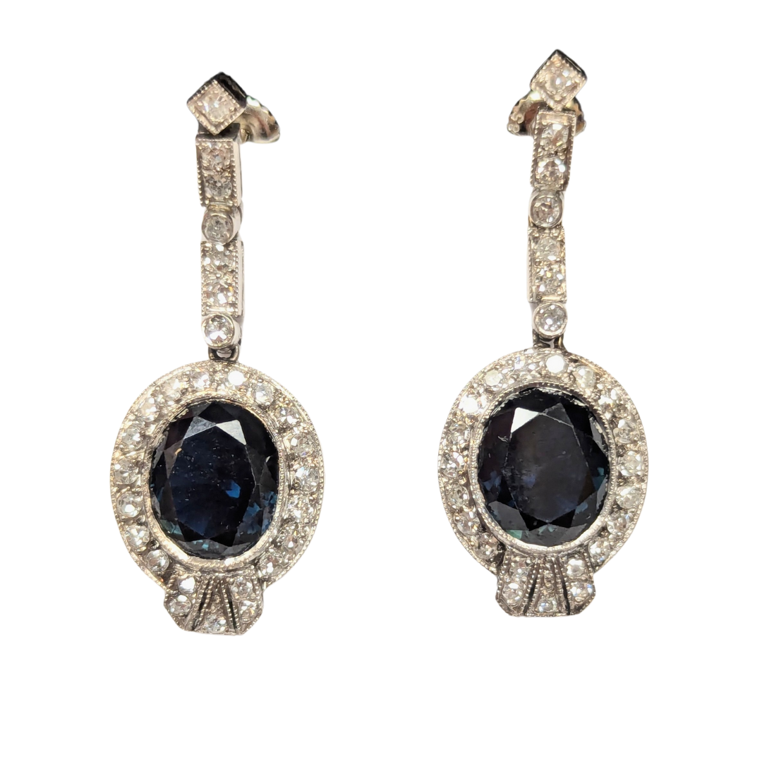 10k white gold drop earrings featuring oval teal sapphires surrounded by sparkling round diamonds.