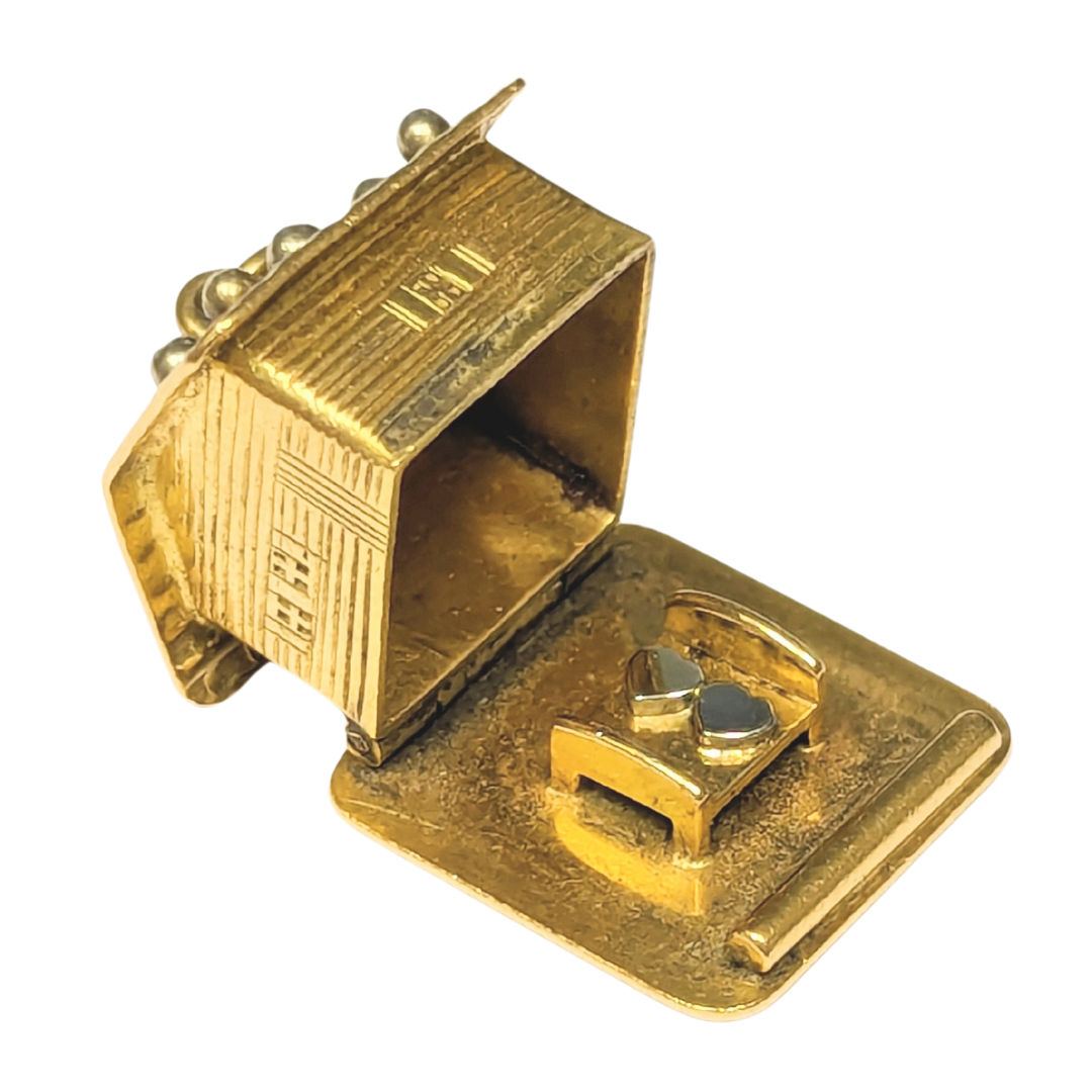14k yellow gold articulating Swiss chalet charm that opens to reveal two heart-shaped figures in a bed.