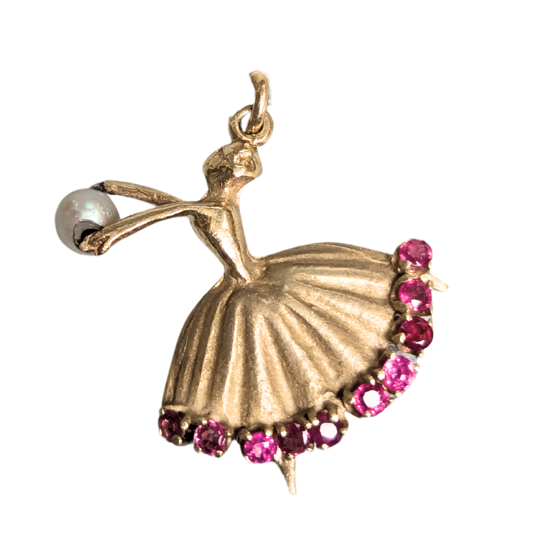 14k yellow gold ballerina charm featuring a ruby-encrusted tutu and a pearl accent in an arabesque pose.