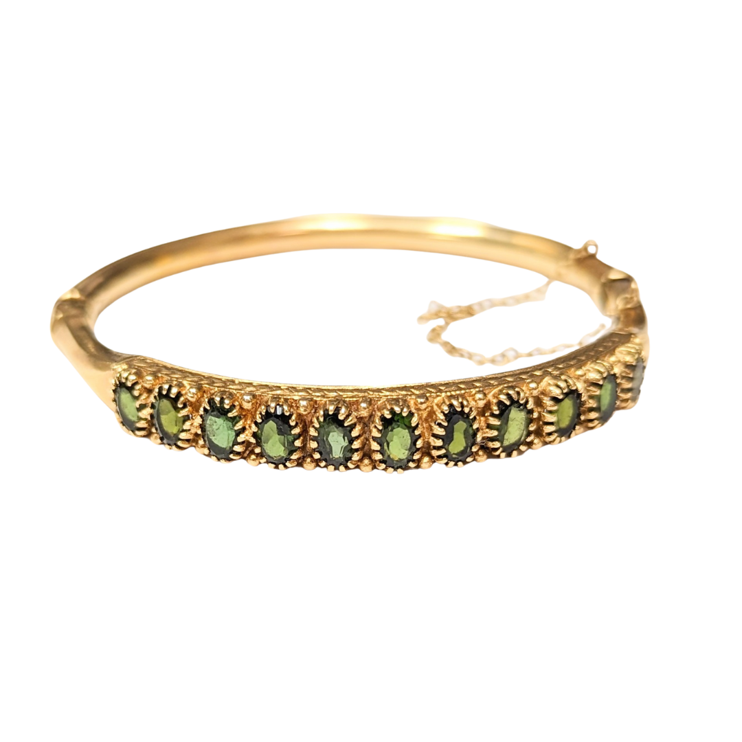 14k yellow gold hinged bangle bracelet featuring 11 oval green tourmaline gemstones in a decorative setting.