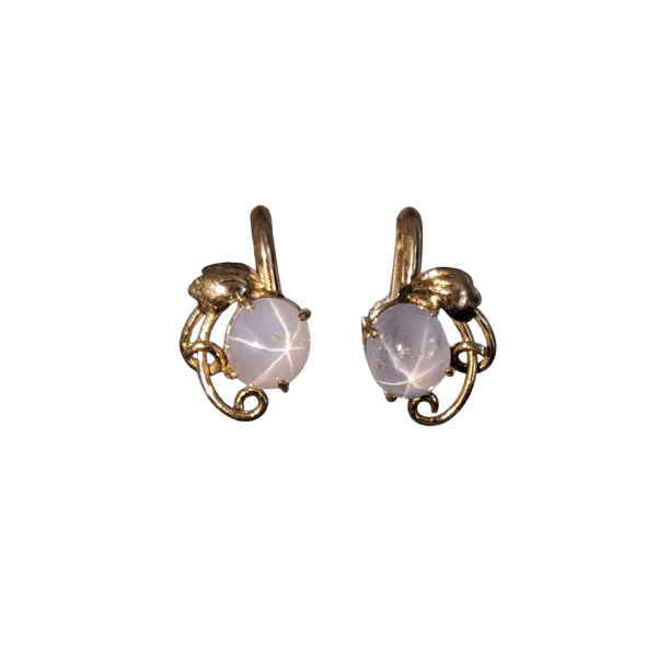 14k yellow gold screwback earrings featuring round pale white star sapphires in an ornate, swirling metal setting.
