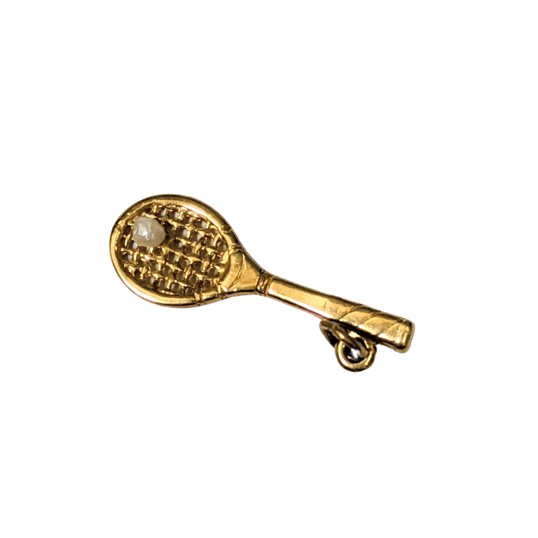 14k yellow gold tennis racquet charm featuring a small 2mm pearl accent as a tennis ball on a textured mesh head.