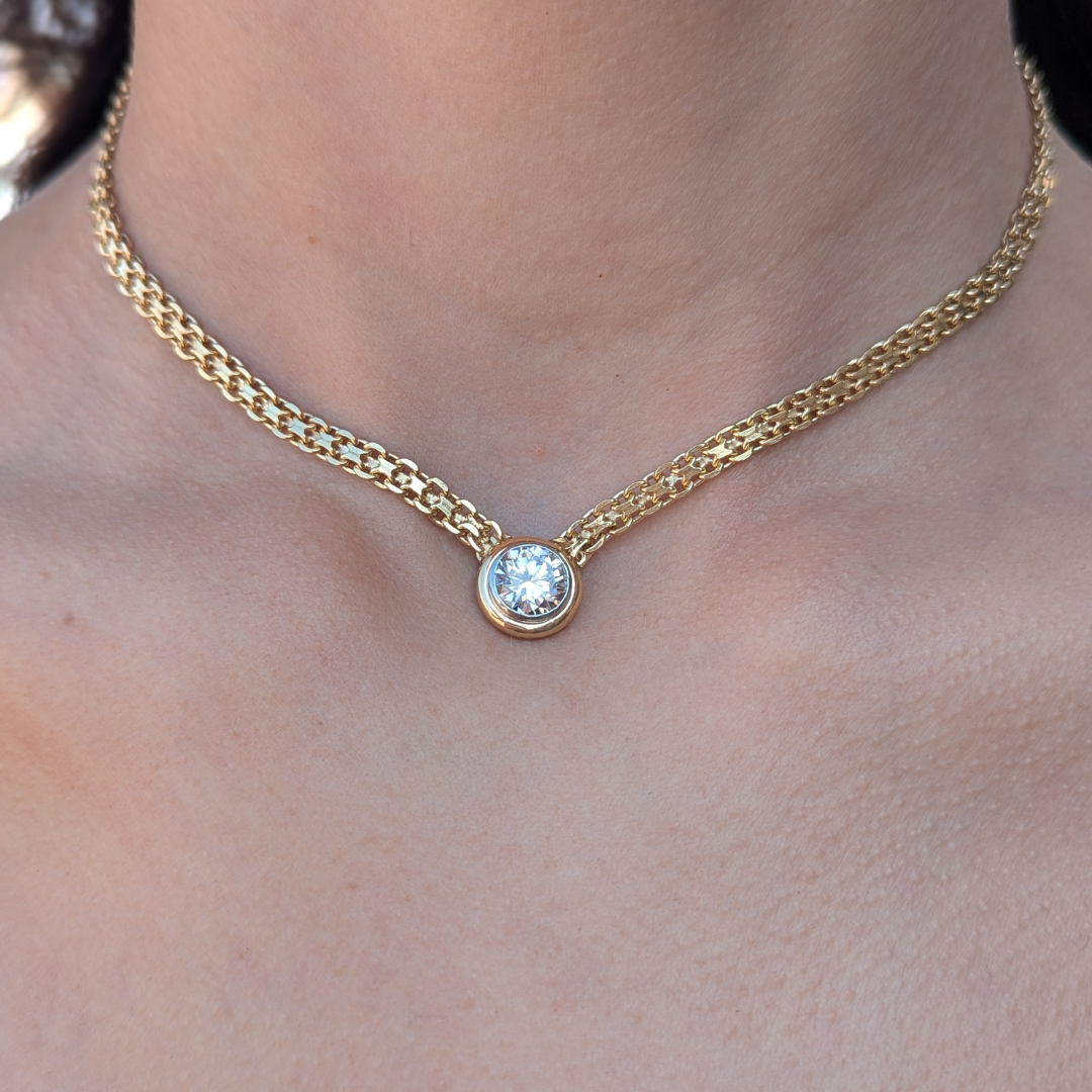 2.31ct round brilliant diamond in a 14k yellow gold bezel setting on a woven X-link chain necklace.