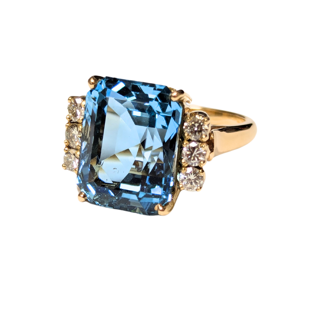 18k yellow gold ring featuring a large emerald-cut aquamarine flanked by six brilliant-cut diamonds.