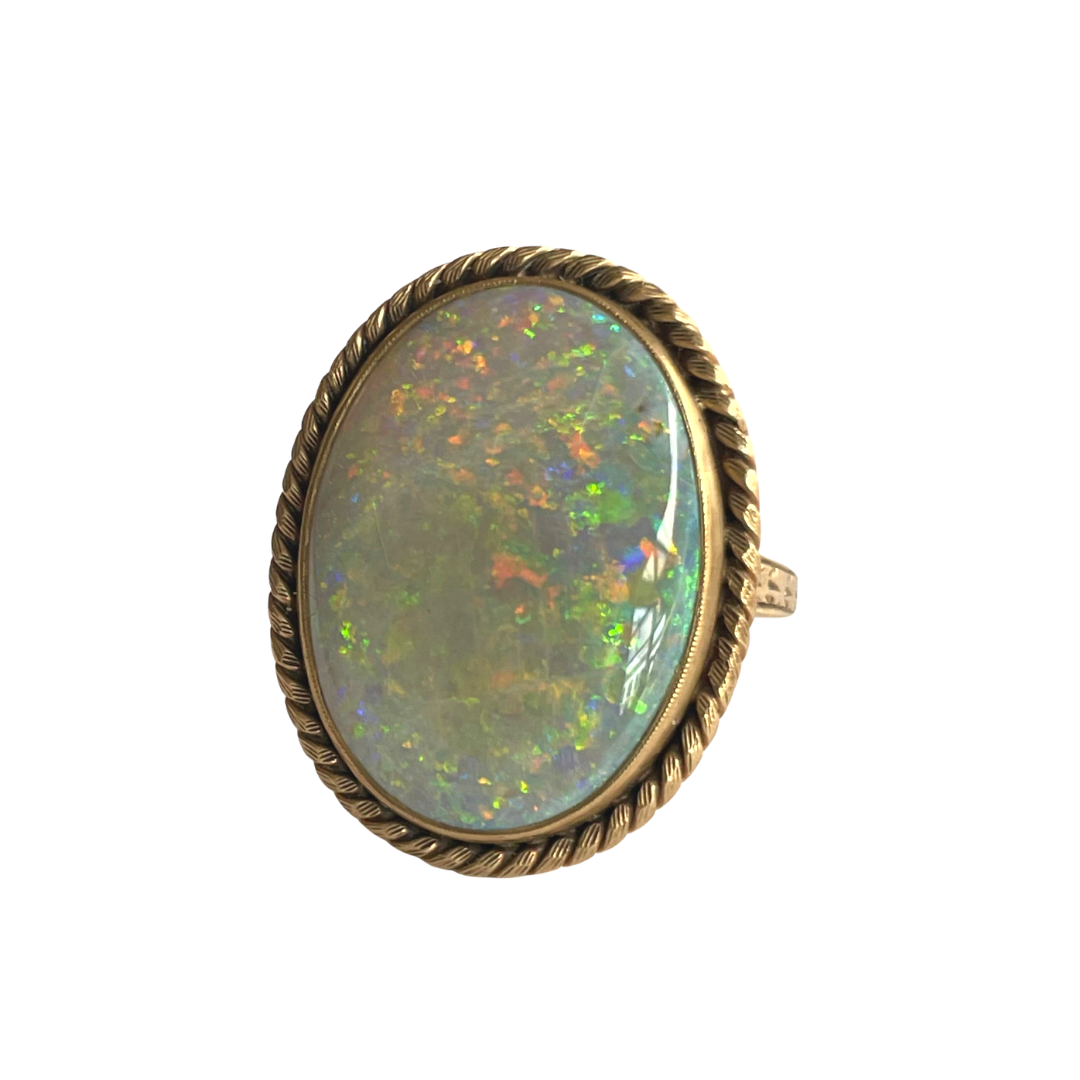 18k yellow gold ring featuring a large oval opal cabochon framed by a twisted rope-edge design.