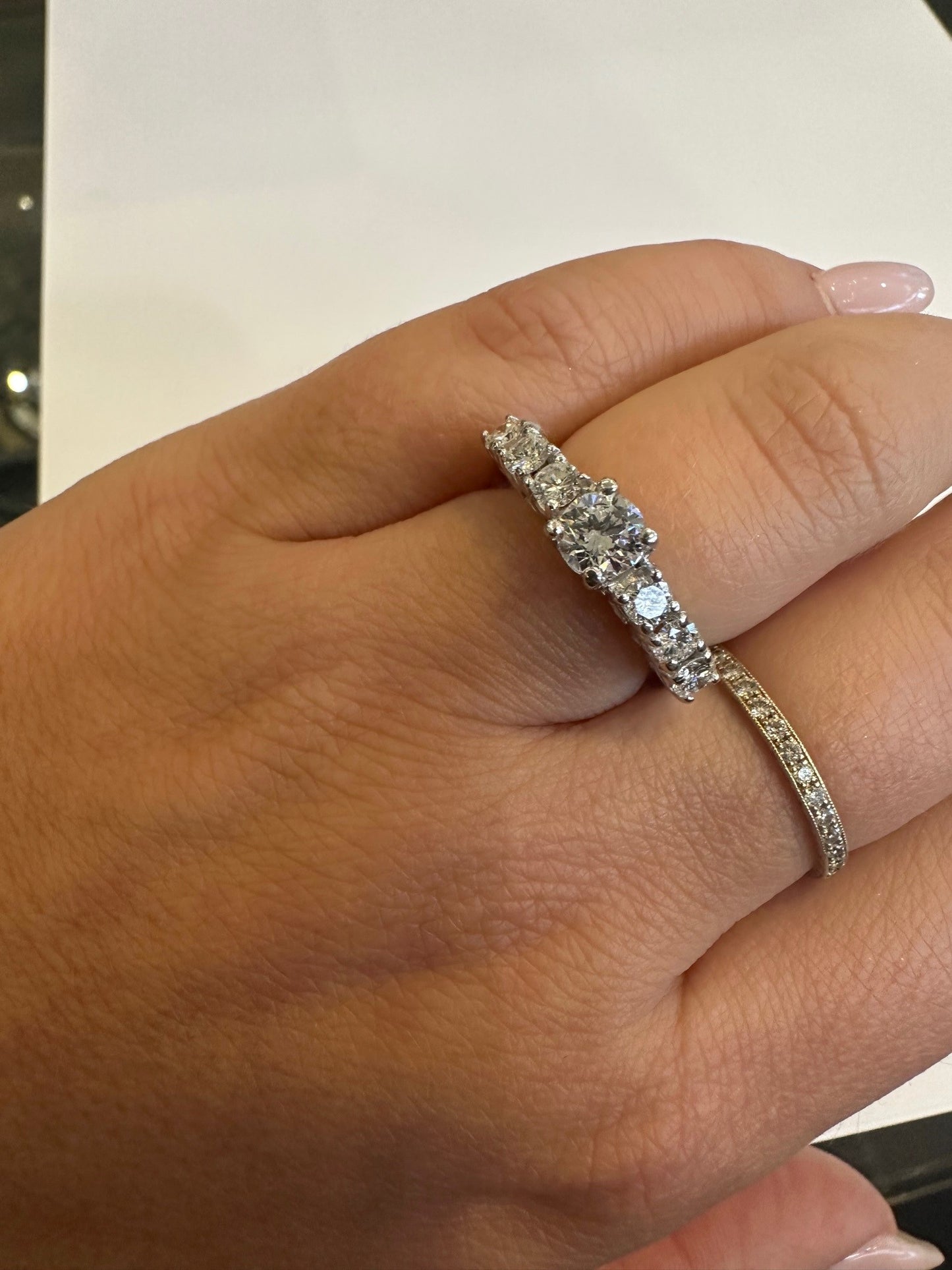 18k white gold seven-stone diamond ring featuring a round center diamond on a finger.