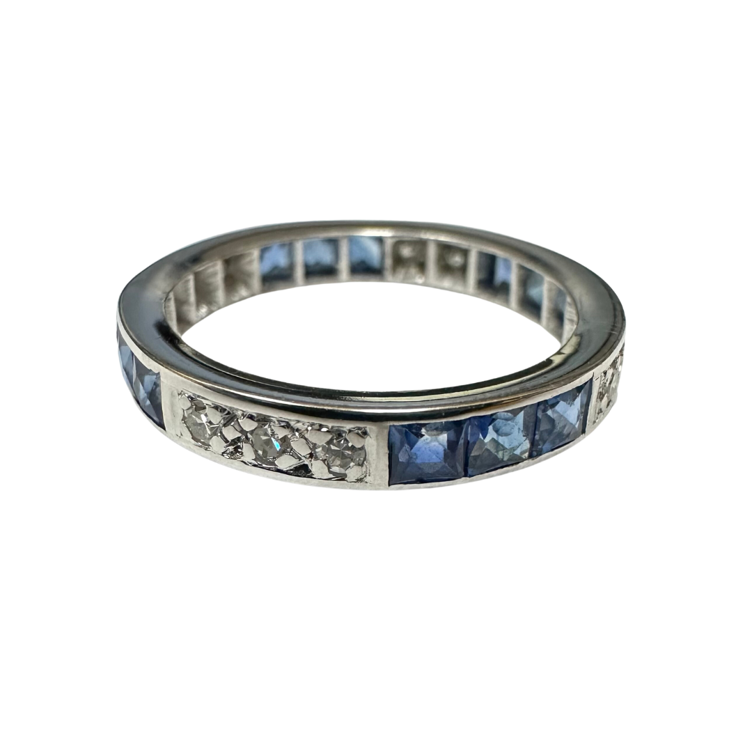 18k white gold eternity band featuring alternating square blue sapphires and single cut diamonds in a 3mm wide setting.