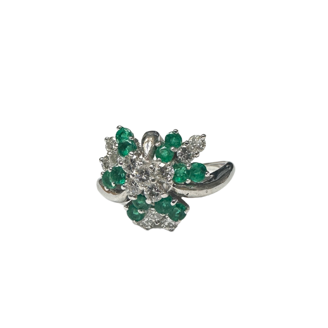 14k white gold cluster ring featuring a round emerald surrounded by sparkling brilliant-cut diamonds.