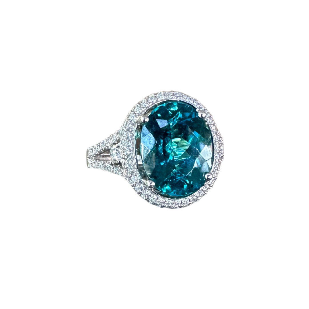 Oval greenish-blue tourmaline ring in 18k white gold with a diamond halo and pavé band.
