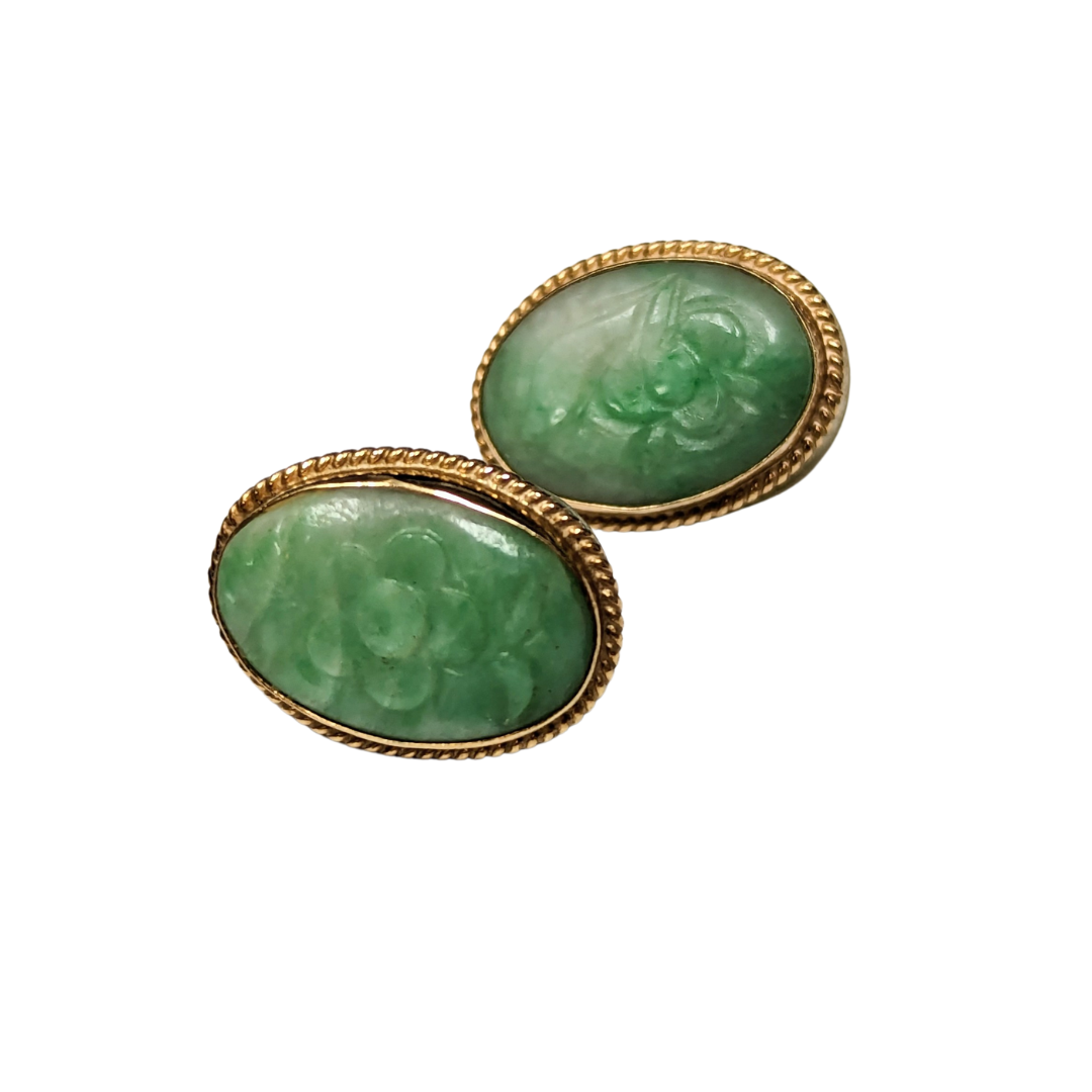 Oval 14k yellow gold stud earrings featuring carved green floral jade centers with a rope-textured border.