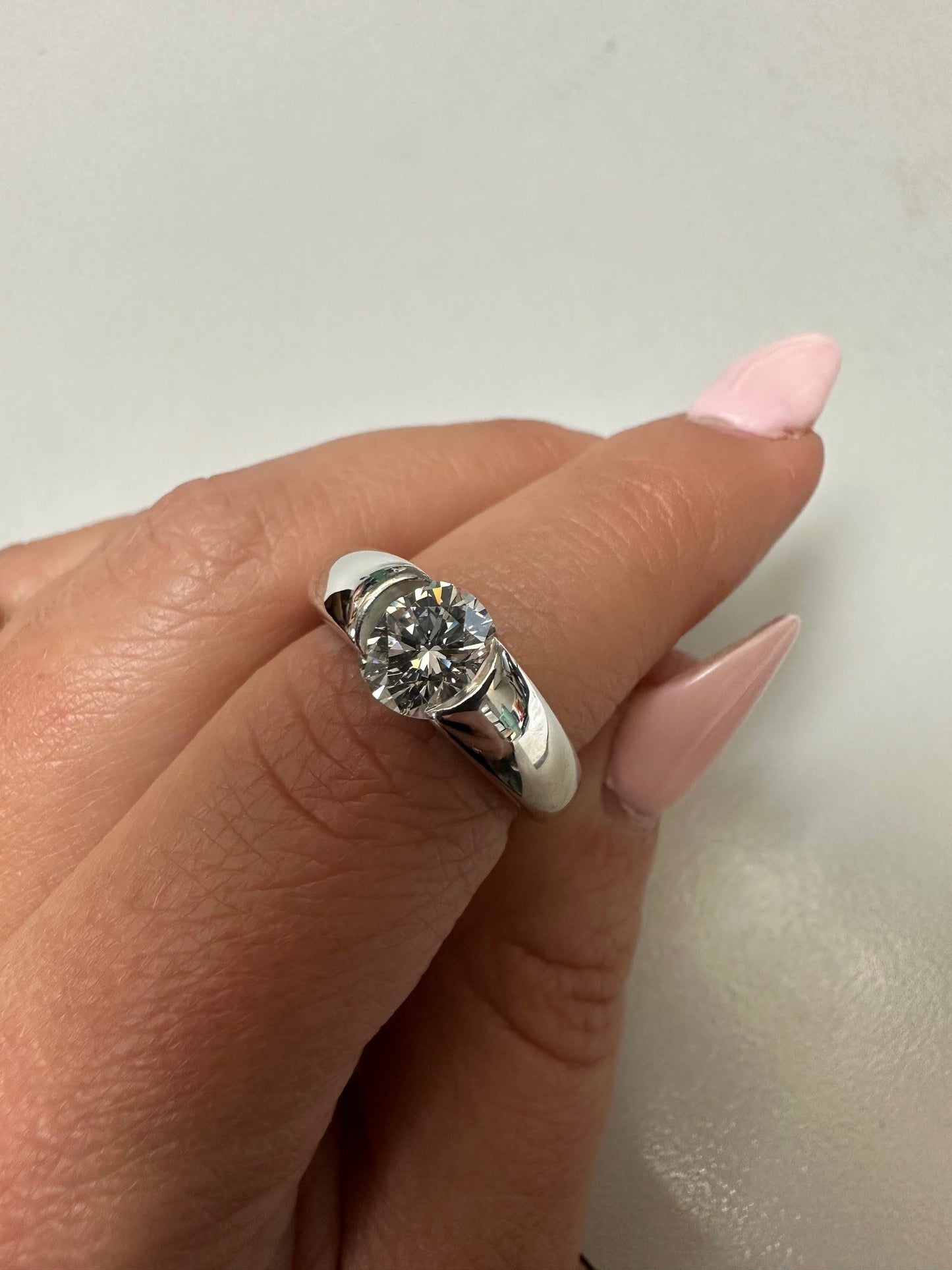 Paul Klecka platinum engagement ring featuring a 1.24 carat round brilliant cut diamond on a finger.