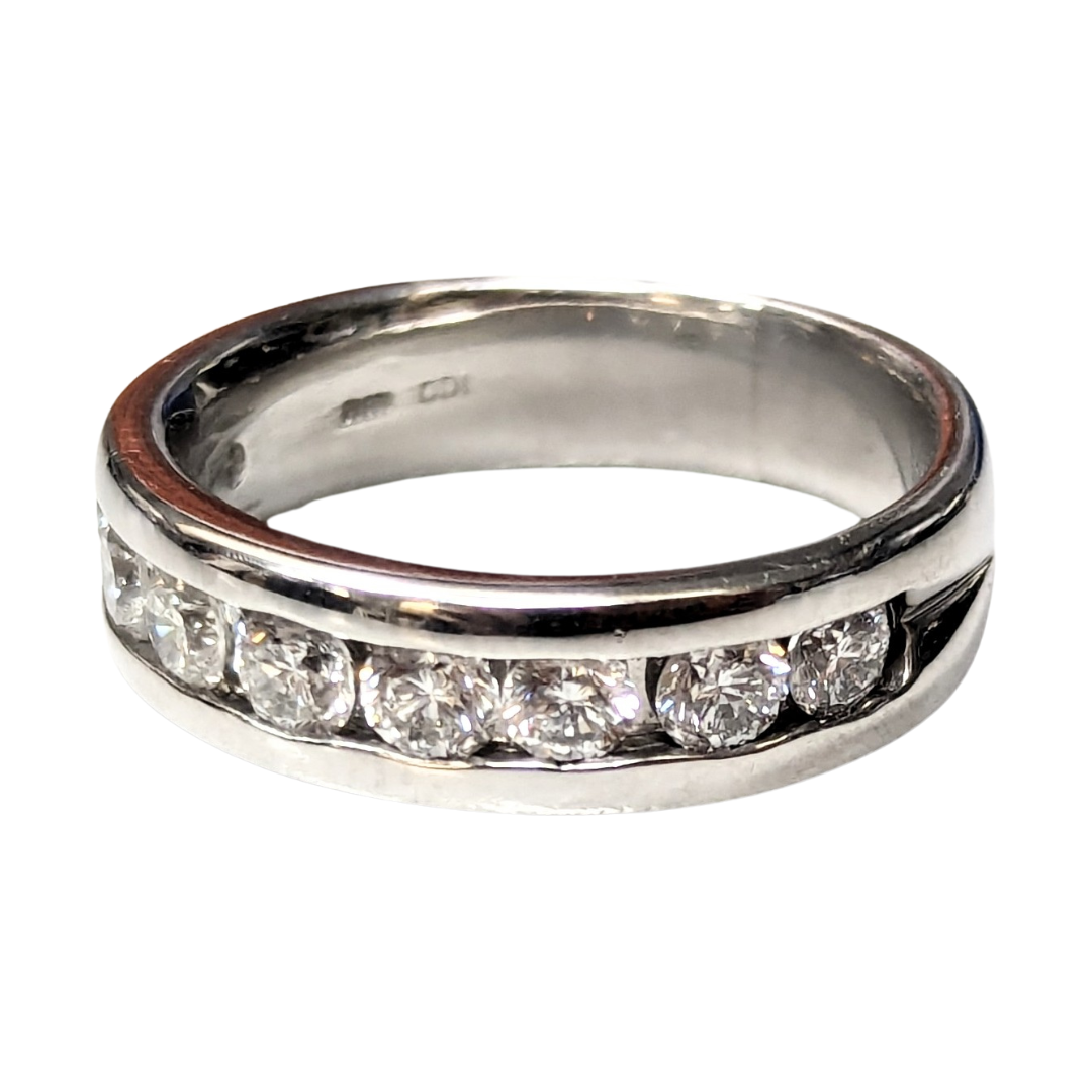 Platinum half-eternity band featuring nine channel-set round brilliant diamonds in a 5.3mm wide polished metal setting.