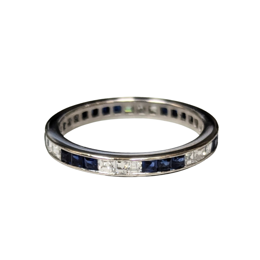 Platinum eternity band with channel-set square blue sapphires and step-cut diamonds.