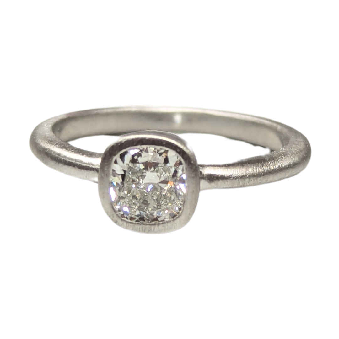 0.60 carat cushion cut diamond solitaire ring in a platinum bezel setting.