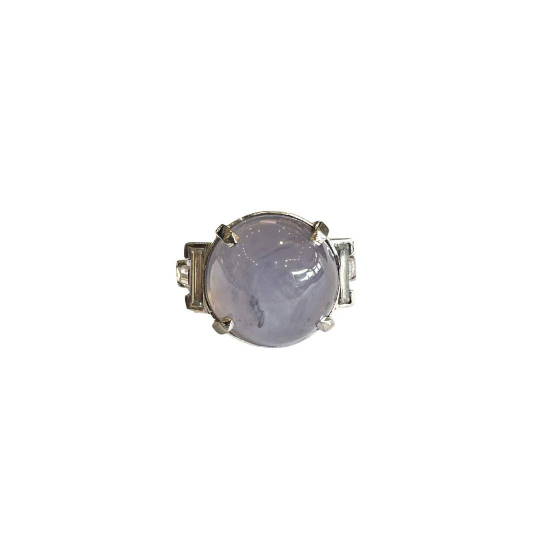 Platinum ring with a large round purple star sapphire accented by four straight baguette cut diamonds.