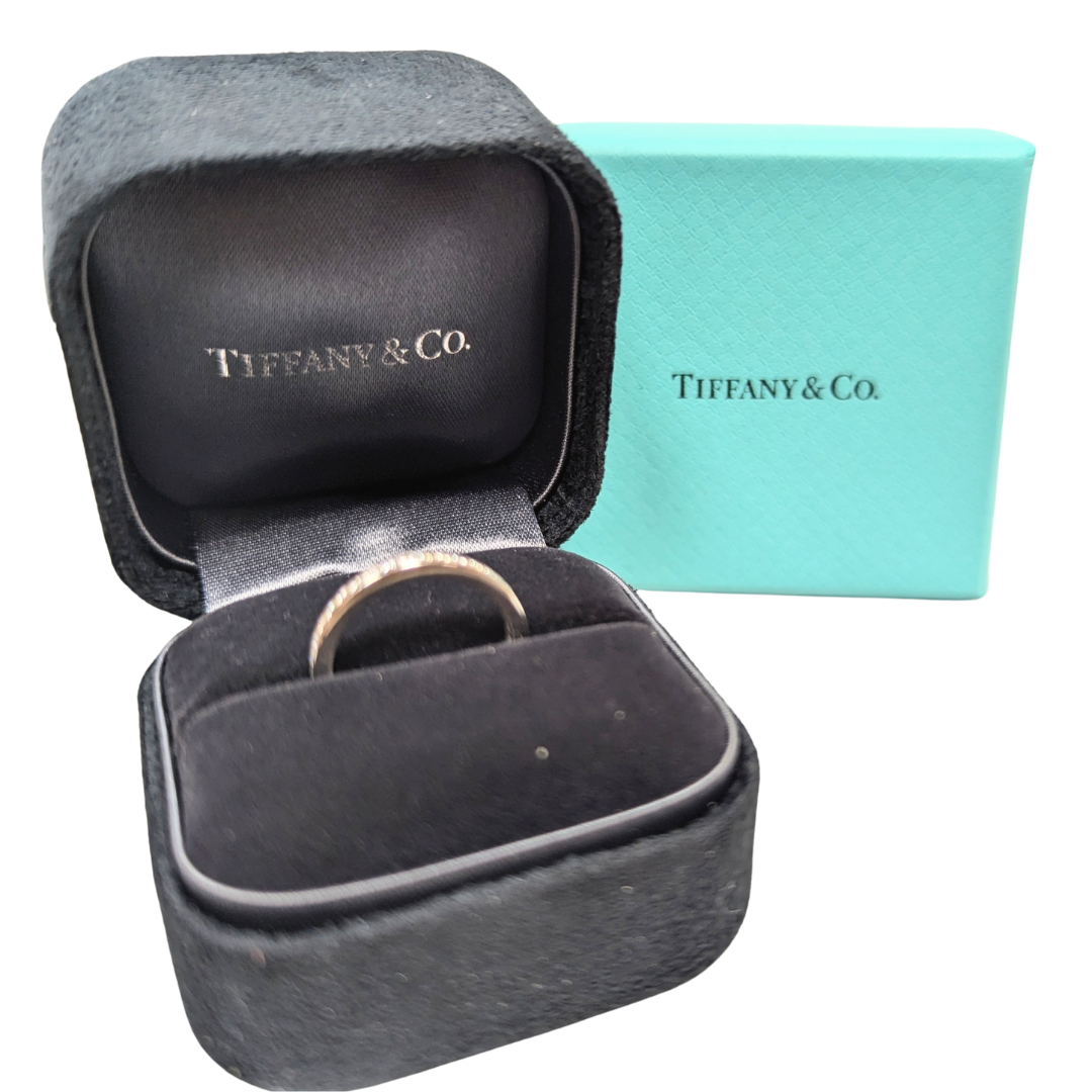 Tiffany & Co. platinum channel-set diamond wedding band in a black velvet box with a signature blue outer box.