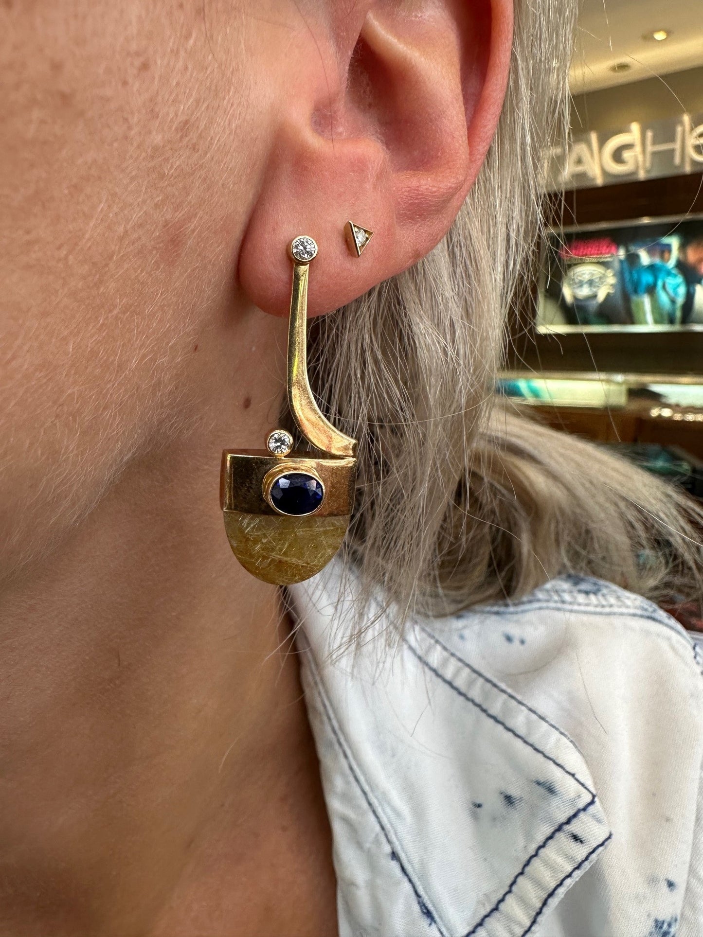 14K yellow gold drop earrings featuring rutilated quartz, oval sapphires, and brilliant cut diamonds worn on an ear.