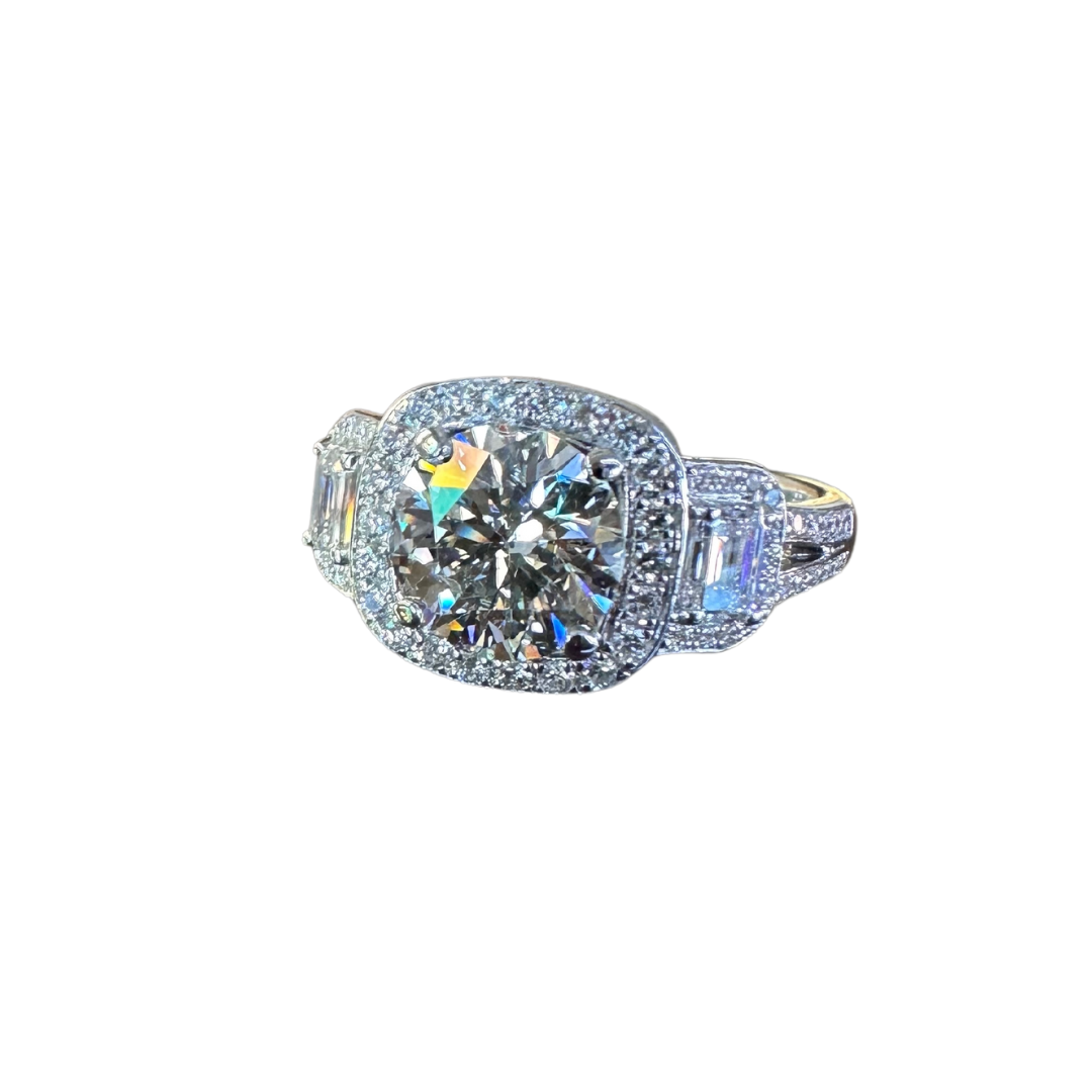 18k white gold three-stone diamond halo ring with a 1.93ct round center stone and emerald-cut side diamonds.