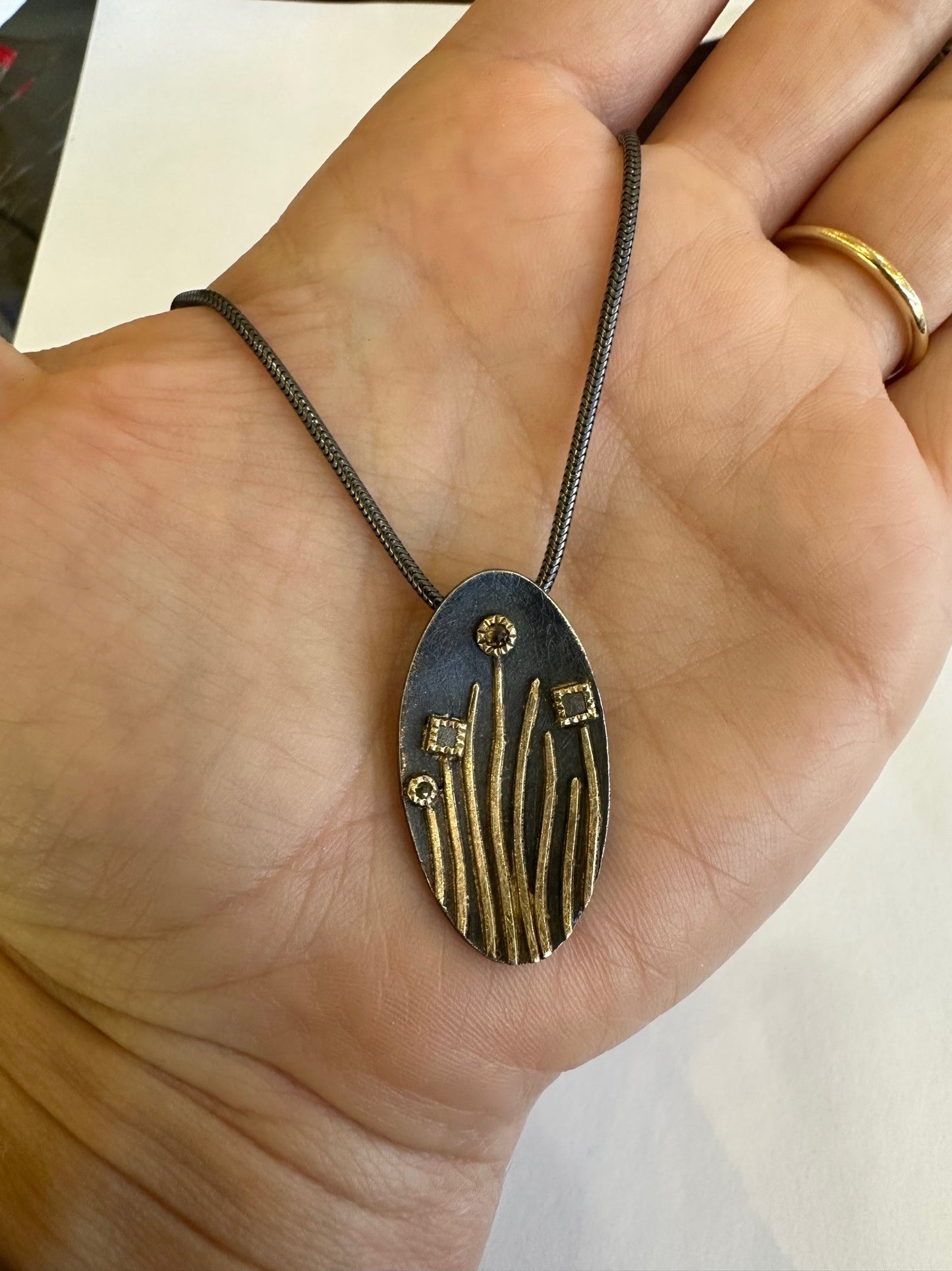 Todd Reed oval pendant in oxidized sterling silver and 18K gold with raw and rose-cut diamonds on a chain.