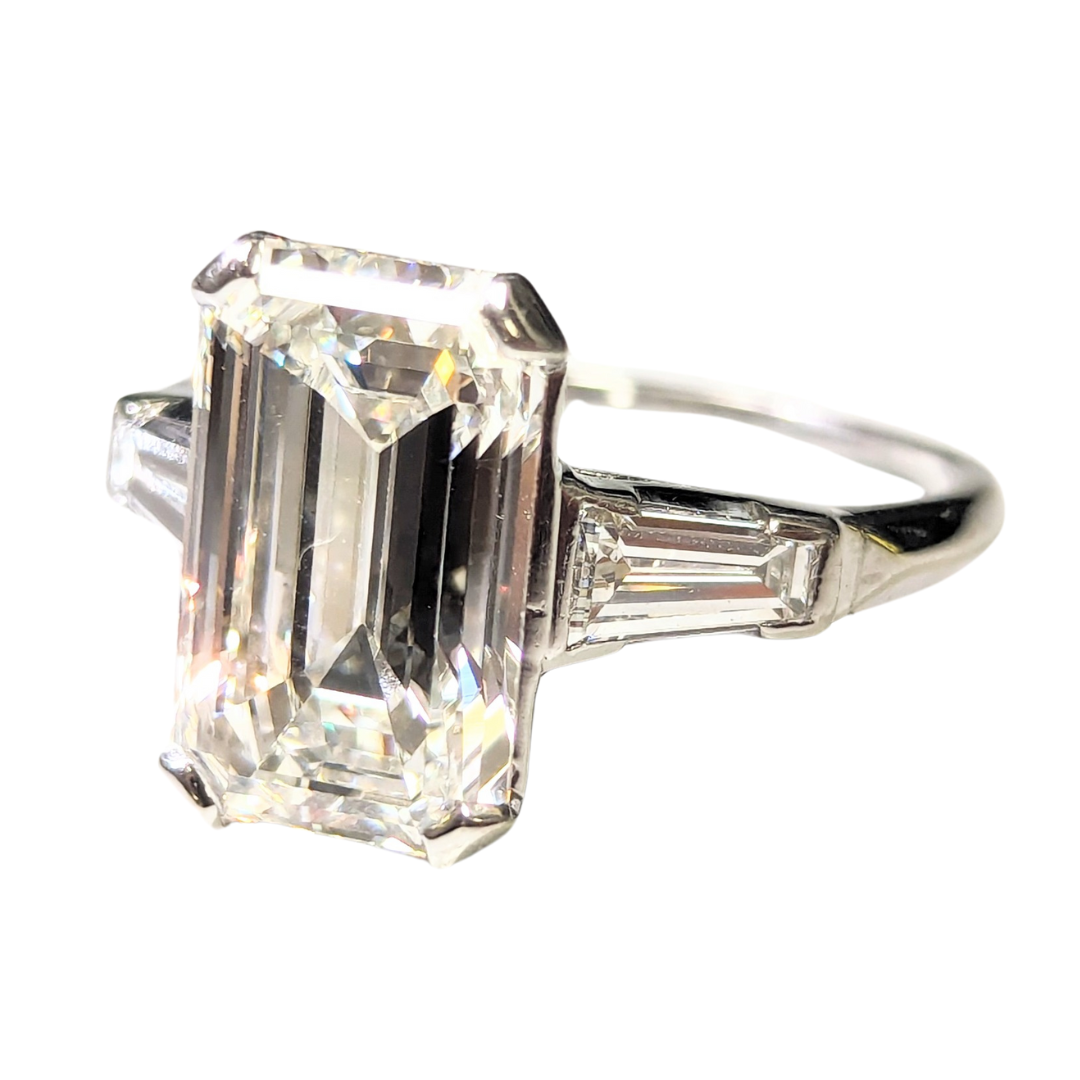 Vintage platinum three-stone ring with a 5.80 carat emerald-cut diamond and tapered baguette side stones.